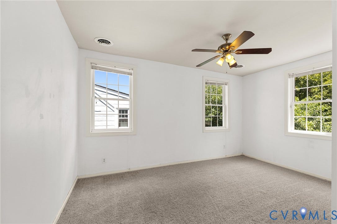 2314 Ingram Avenue, Richmond, VA 23224 Neutral tone wall finishes, gray carpet, three double-hung windows, and a ceiling fan with integrated lighting