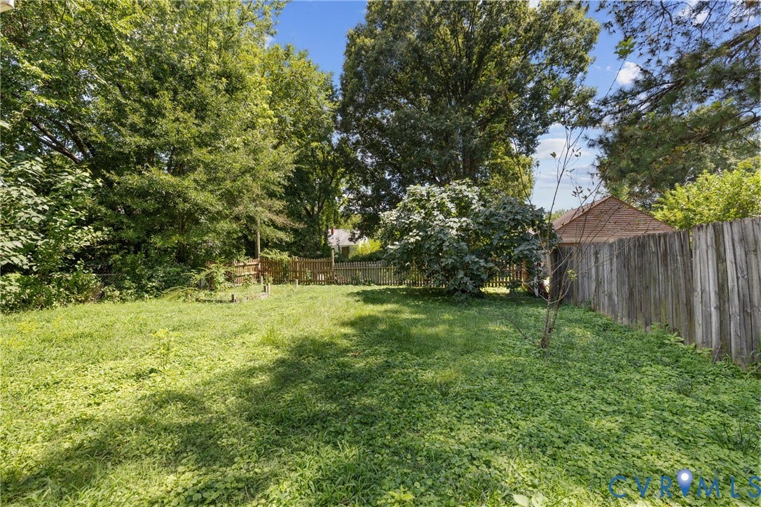 2314 Ingram Avenue, Richmond, VA 23224 Expansive backyard featuring a wood fence, mature trees, and natural landscaping