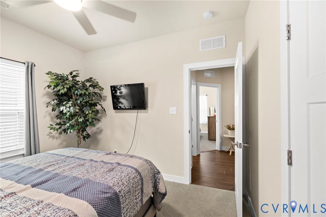 11319 Vulcan Lane, Bermuda, Chester, VA 23831 Ceiling fan, wall-mounted television, neutral wall color, white trim, and wood-finish flooring visible through doorway