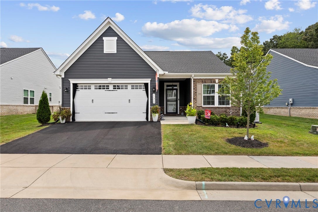 11319 Vulcan Lane, Bermuda, Chester, VA 23831 Dark gray siding exterior with a white trim gable, brick accents, an attached garage, and a concrete driveway
