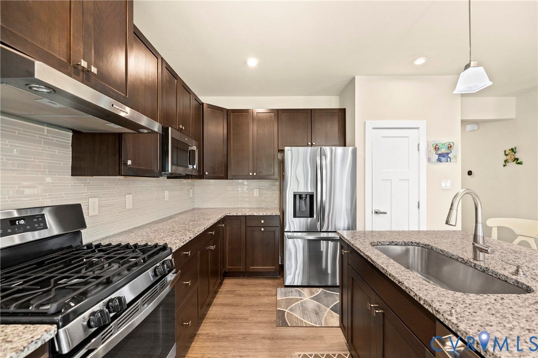 11319 Vulcan Lane, Bermuda, Chester, VA 23831 Kitchen featuring dark wood cabinetry, light-colored granite-style countertops, stainless steel appliances, a white subway tile backsplash, and wood-finish flooring