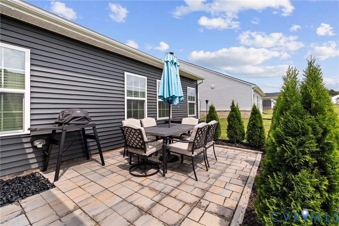 11319 Vulcan Lane, Bermuda, Chester, VA 23831 Paver patio with a dark mulch landscaping bed, featuring mature evergreen plantings and dark siding