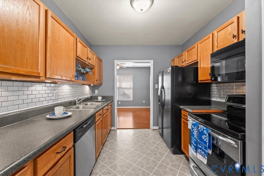 2723 Goyne Terrace, Chester, VA 23831 Galley kitchen featuring wood cabinetry, subway tile backsplash, dual basin stainless steel sink, and stainless steel appliances