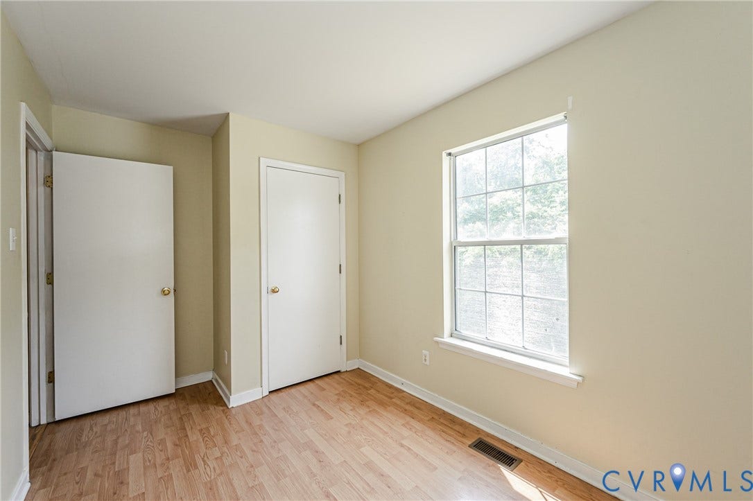 Wood-finish flooring with light-toned walls, white trim, and a multi-pane window