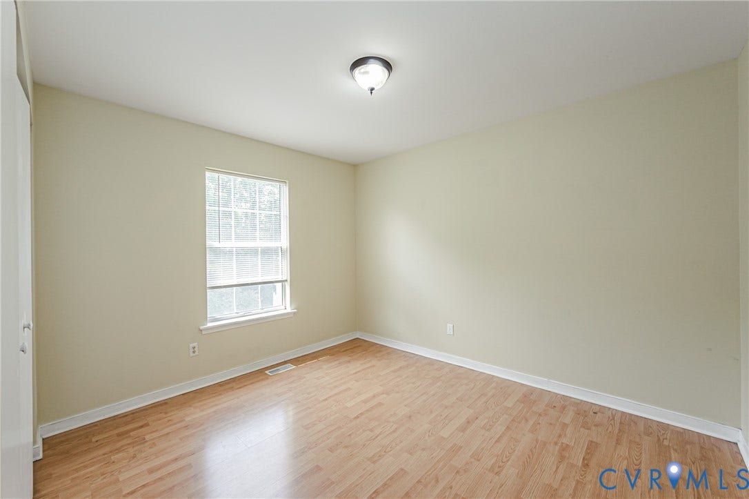 Neutral wall paint, wood-finish flooring, and a single window