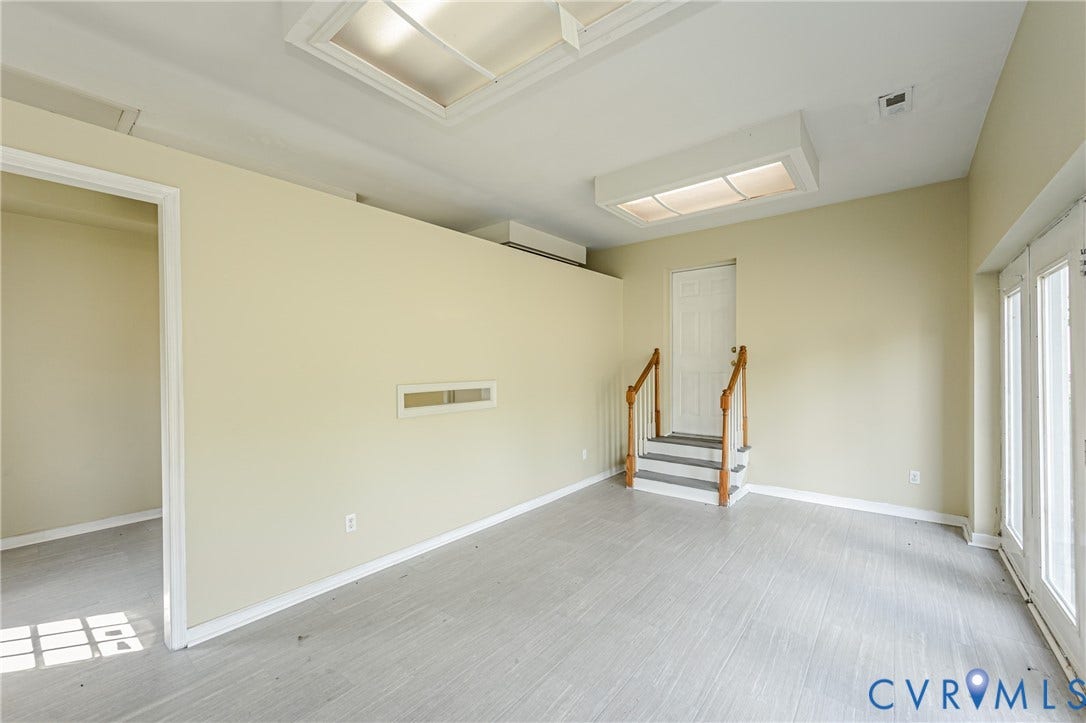 Light wood-finish flooring, recessed lighting, skylights, white French doors, and a built-in staircase with wood railings