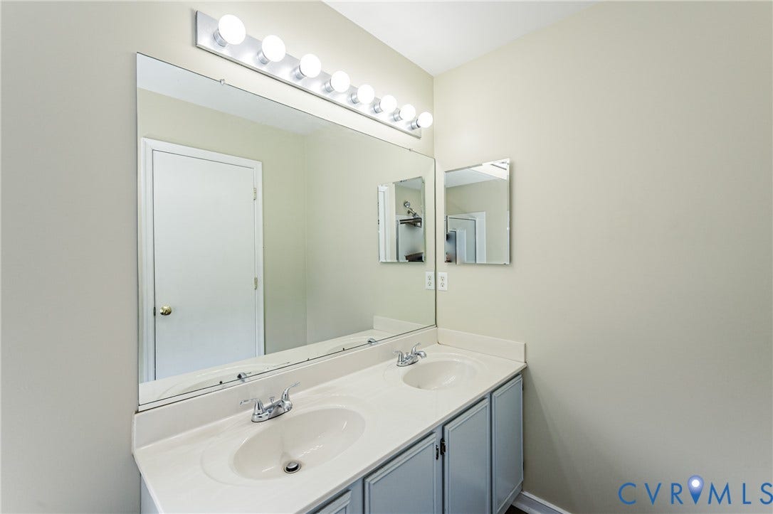 Double vanity with integrated sinks, chrome faucets, and light gray cabinetry