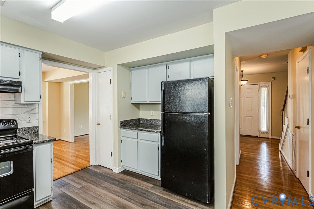 Kitchen featuring wood-finish flooring, light-toned cabinetry, and dark countertops