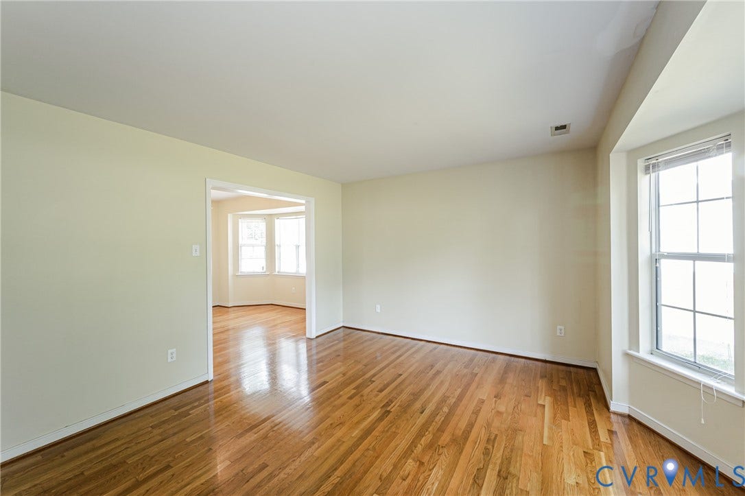 Hardwood flooring throughout, neutral wall tones, and a bay window