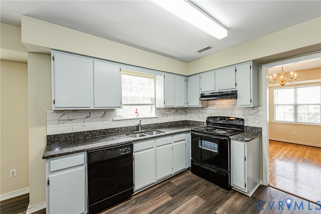Kitchen featuring wood-finish flooring, white cabinetry, dark countertops, and a subway tile backsplash