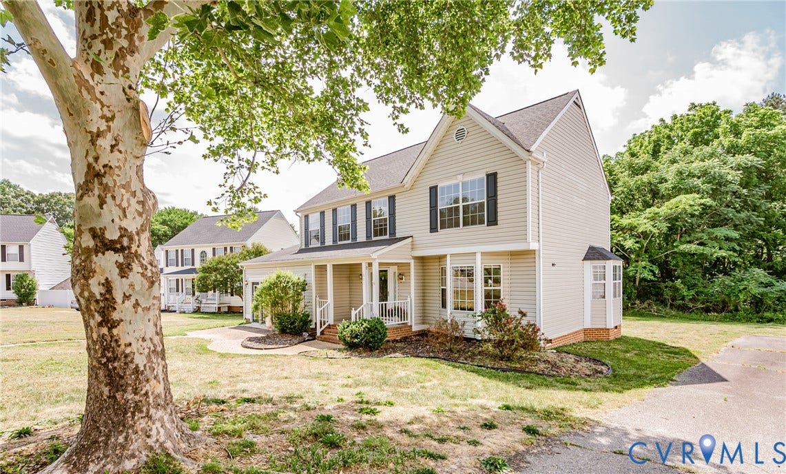 Two-story residence featuring light-colored siding, a covered front porch, and a bay window