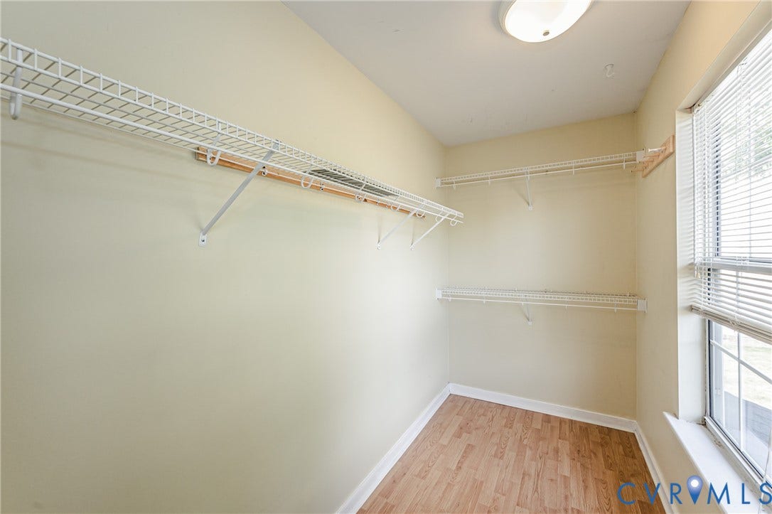 Recessed lighting, wood-finish flooring, multiple wire shelving units, and a window with blinds