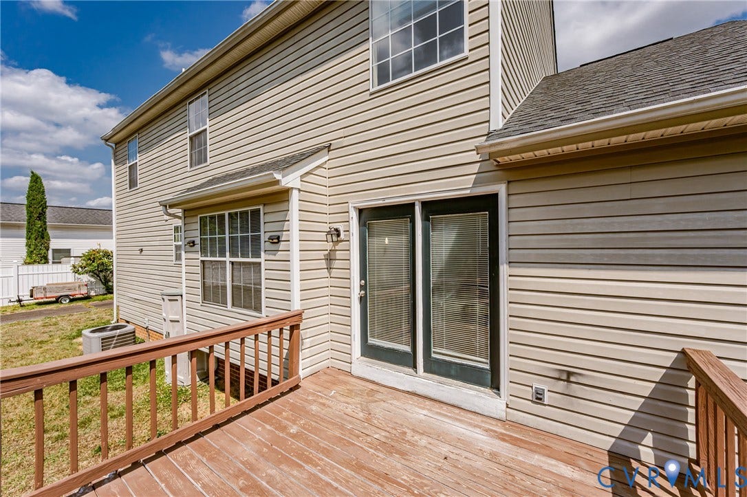 Expansive wood-finish deck with railing, siding exterior, black-frame glass panel door, and multiple windows