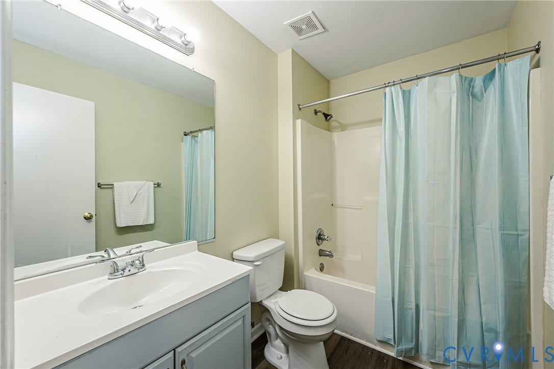 Single-sink vanity with light-toned countertop, wall-mounted mirror, overhead lighting, and a white tub/shower combination