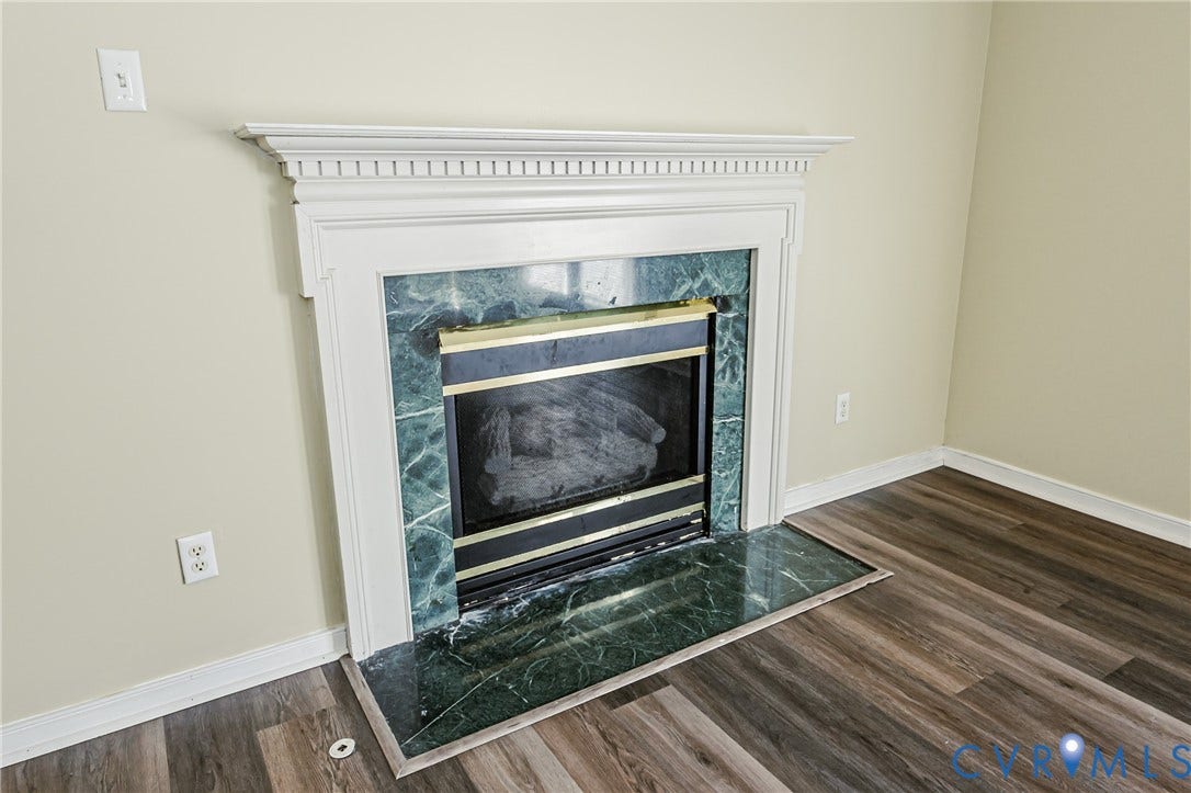 Fireplace with a white wood mantel, green veined surround, and a matching hearth