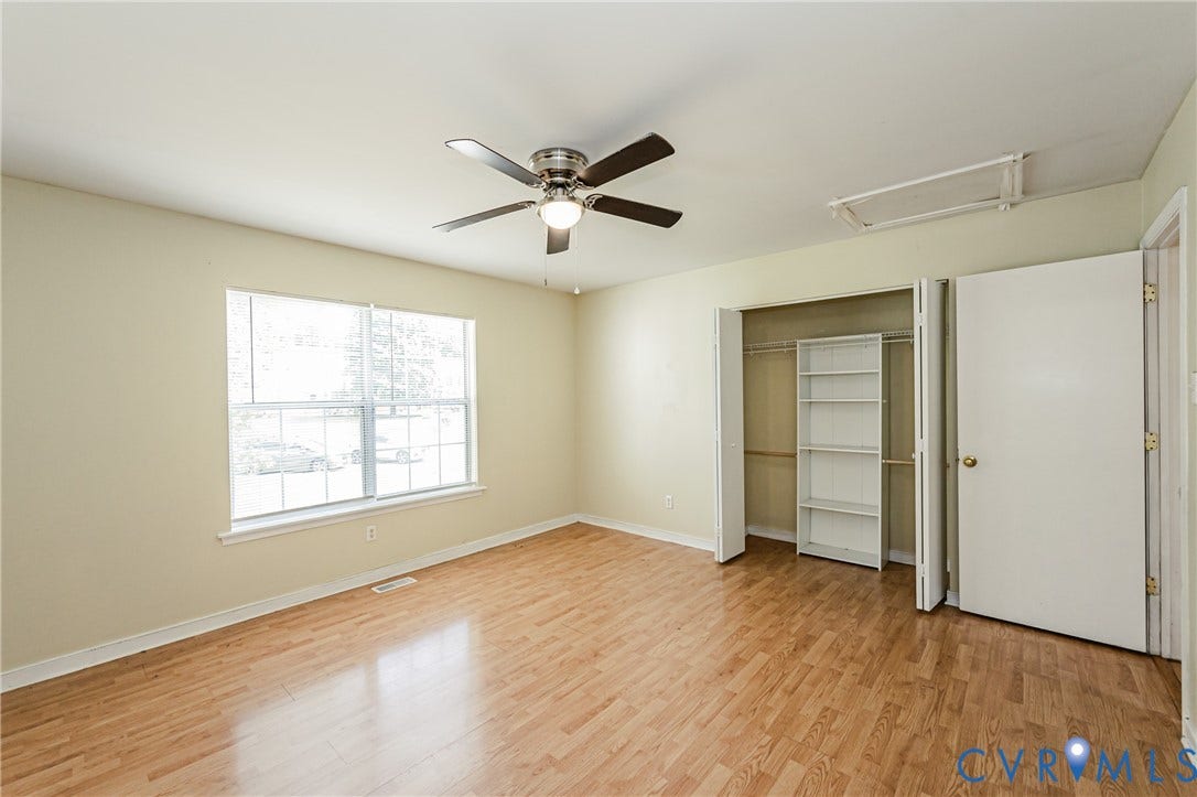 Wood-finish flooring, ceiling fan with integrated lighting, double-pane window, bi-fold closet doors, and built-in closet shelving