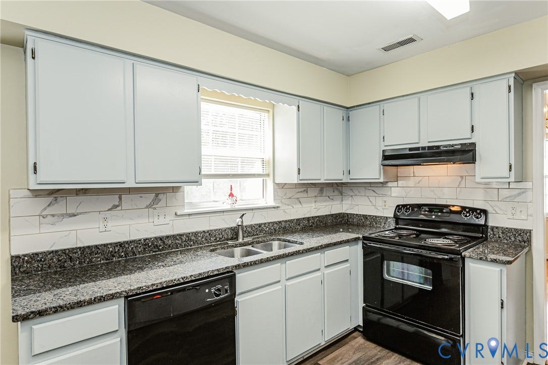 Kitchen featuring light-toned cabinetry, dark granite-style countertops, white subway tile backsplash, and wood-finish flooring