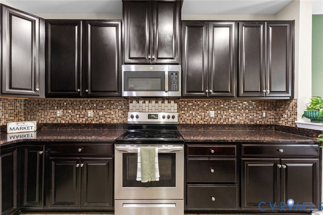 5112 Weatherby Drive, Chester, VA 23831 Dark wood-finish cabinetry, mosaic tile backsplash, dark countertop, stainless steel appliances, and an electric range