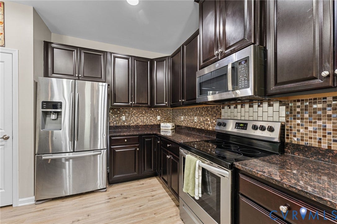 5112 Weatherby Drive, Chester, VA 23831 Dark wood-finish cabinetry, stainless steel appliances, mosaic tile backsplash, speckled countertops, and wood-finish flooring