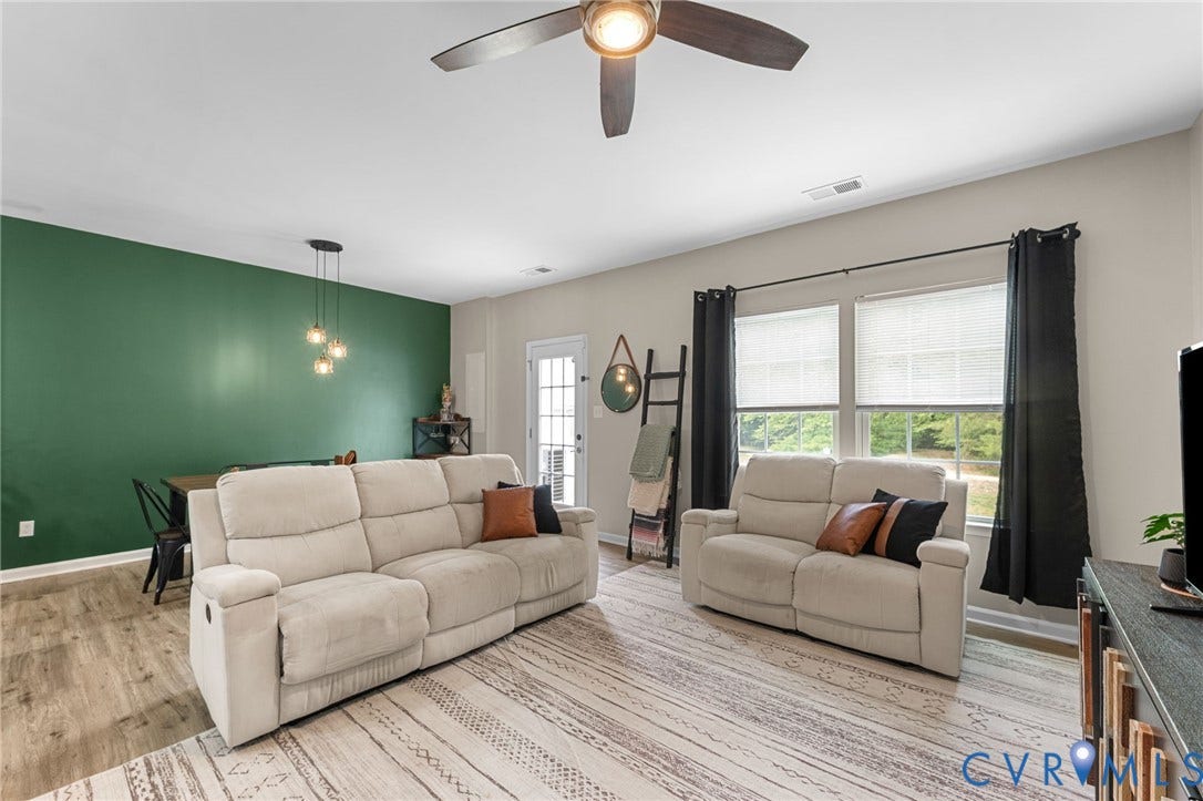 5112 Weatherby Drive, Chester, VA 23831 Open-concept living area featuring a ceiling fan, a prominent accent wall, dual windows with blinds, a glass-paned door, and wood-finish flooring