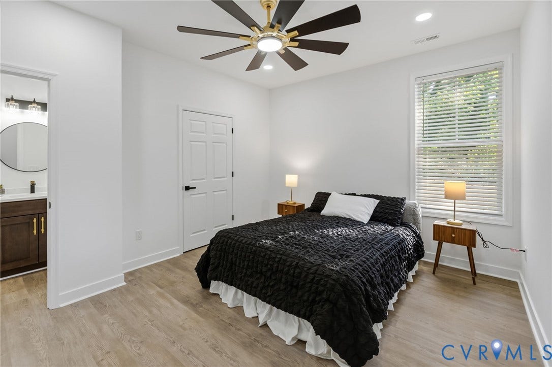 524 Cameron Street, Petersburg, VA 23803 Bright secondary bedroom featuring wood-finish flooring, a contemporary ceiling fan with integrated lighting, large operable window with plantation shutters, and direct access to an ensuite bathroom