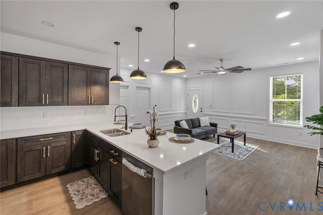 524 Cameron Street, Petersburg, VA 23803 Open-concept living area featuring a kitchen island with pendant lighting, wood-finish flooring, dark wood cabinetry with gold-tone hardware, and white wall paneling