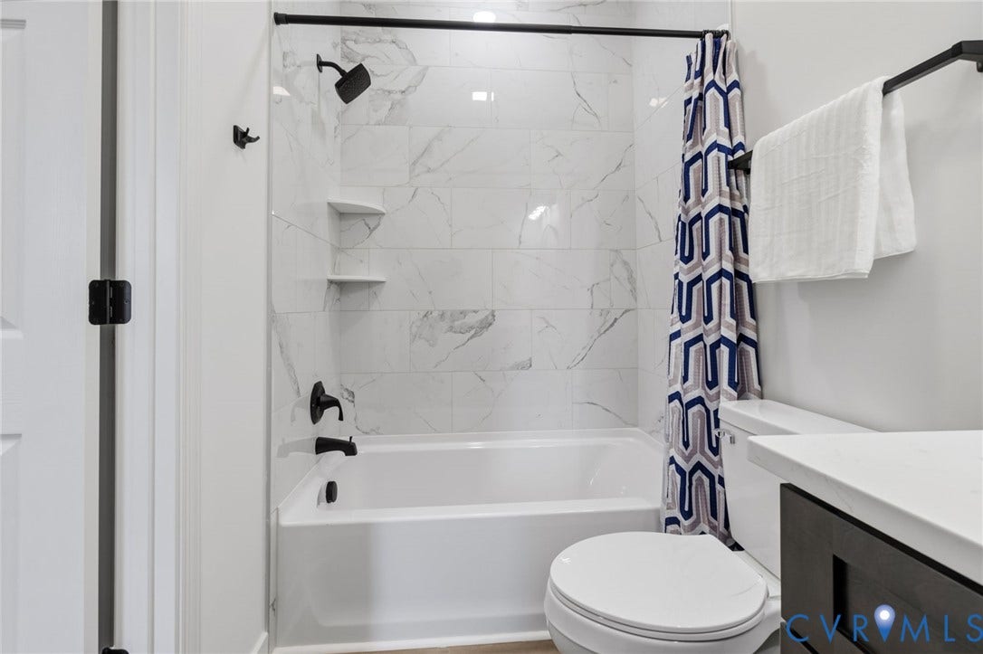 524 Cameron Street, Petersburg, VA 23803 White bathtub with a matte black showerhead and faucet, set against a tiled wall with a marble-like pattern