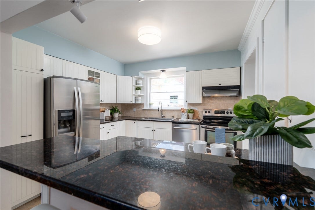 Kitchen featuring dark stone countertops, stainless steel appliances, white cabinetry, a built-in microwave, and an undermount sink