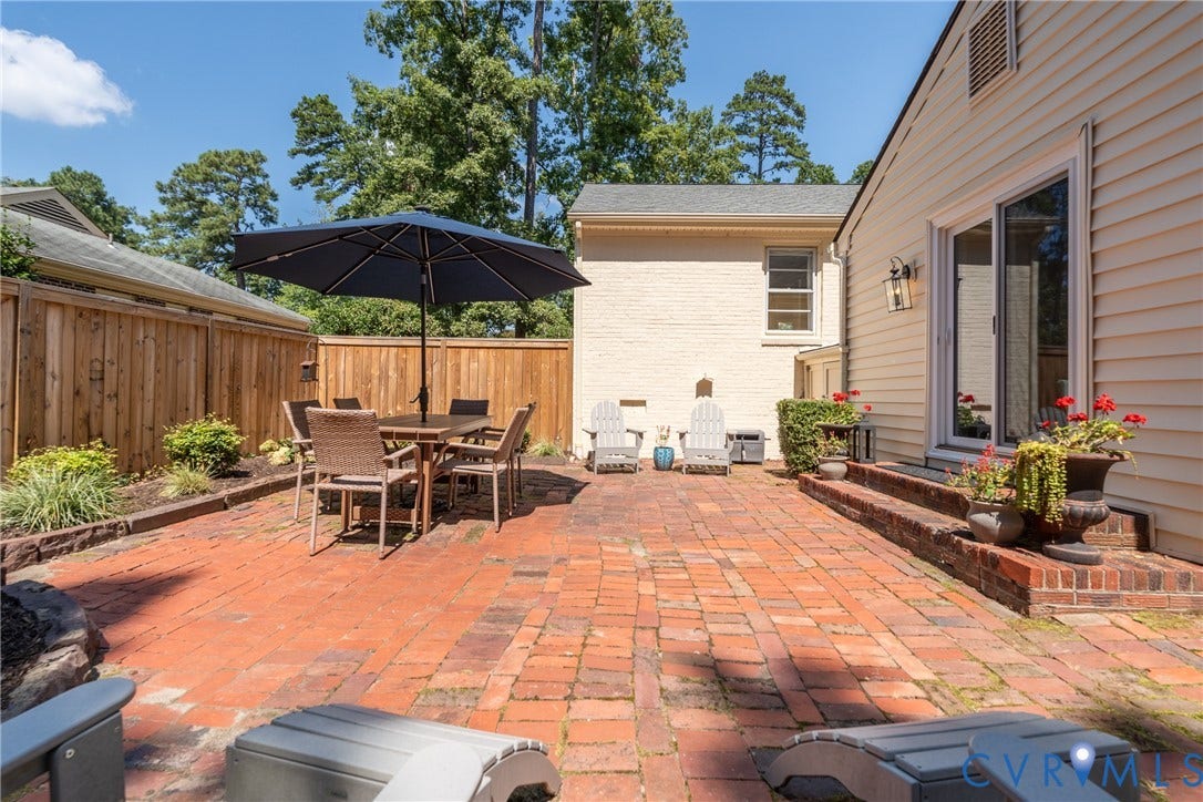 Expansive brick patio featuring a privacy fence, landscaping, and a sliding glass door entry