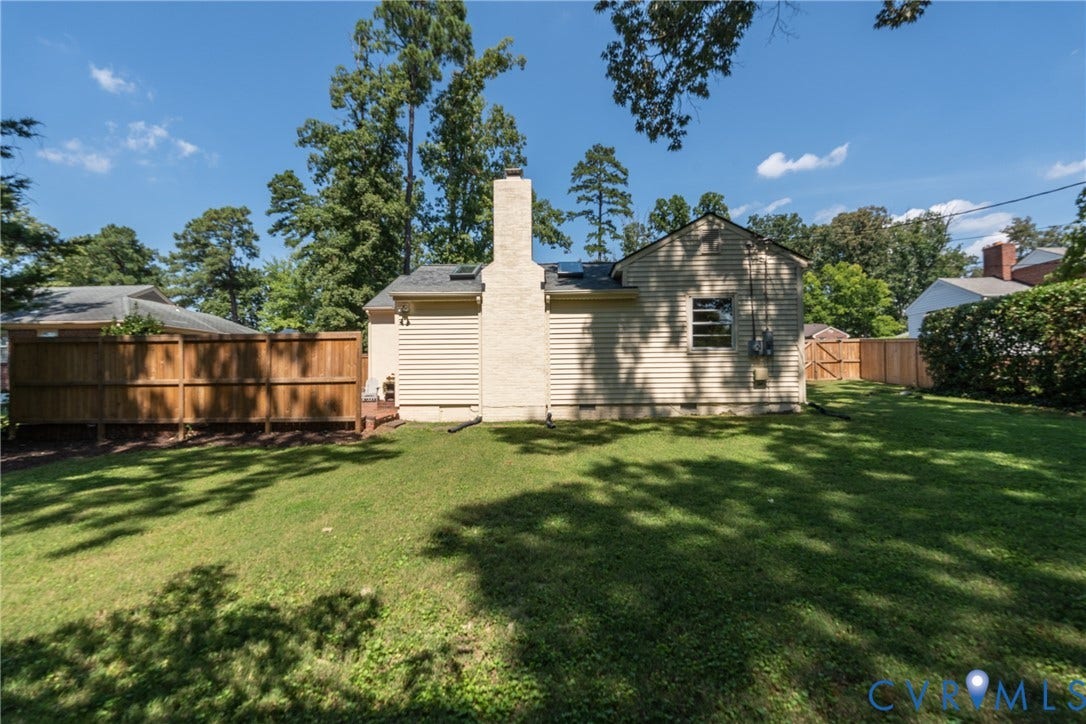 Expansive grassed yard with a wood privacy fence and mature trees