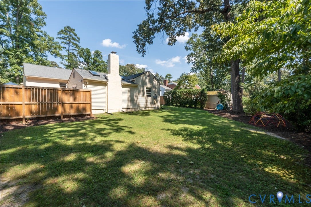 Expansive backyard with a manicured lawn, established trees, privacy fencing, and a detached storage shed