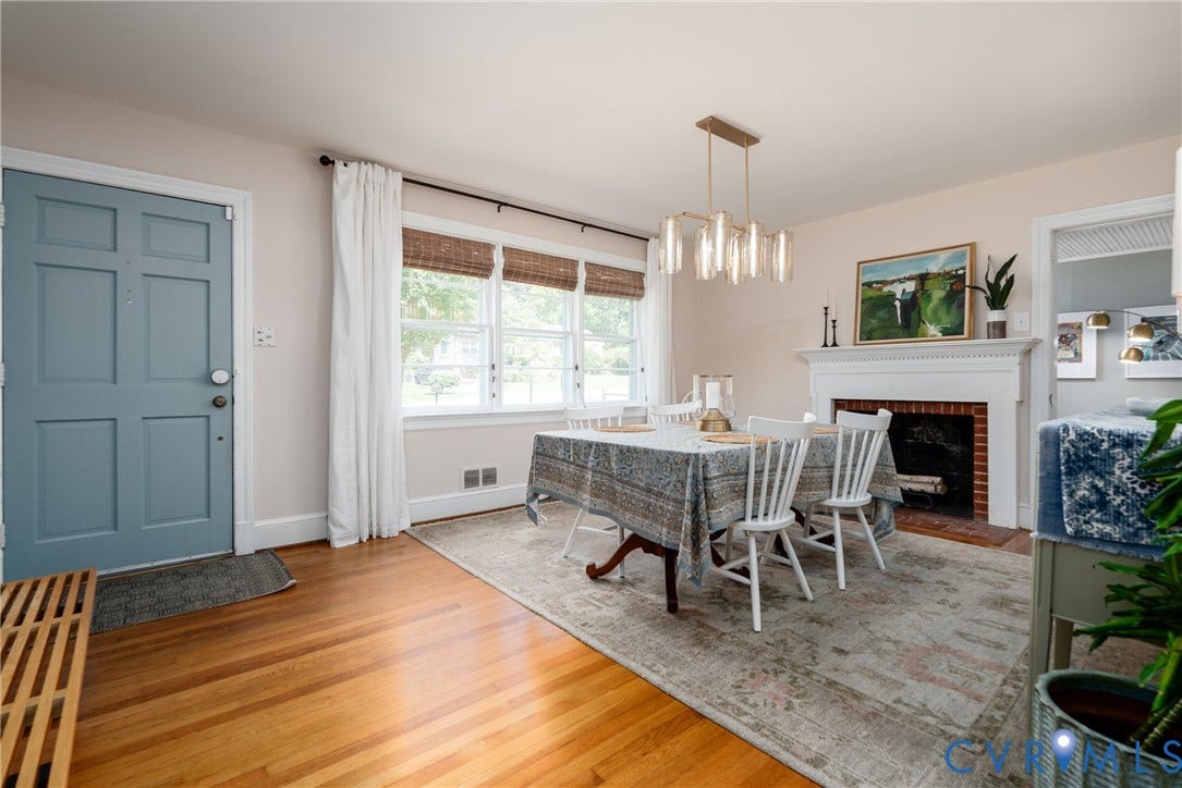 Hardwood flooring, multi-pane windows with woven shades, fireplace with a white mantel, and a contemporary linear chandelier