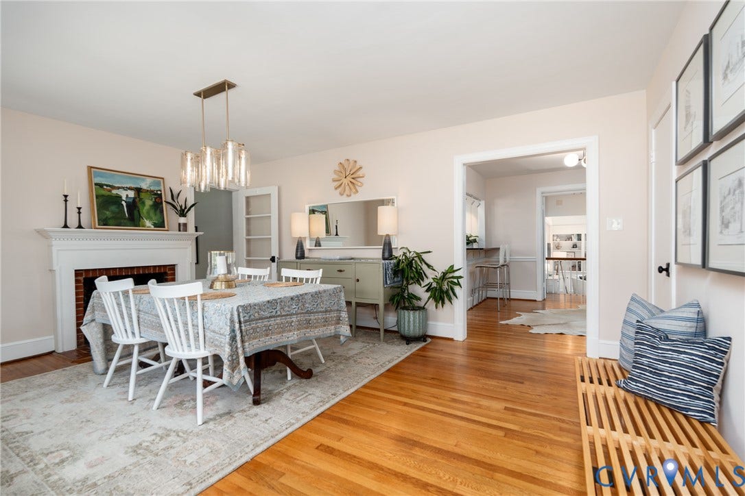 Hardwood flooring throughout, featuring a decorative fireplace with a white mantel, and a modern chandelier