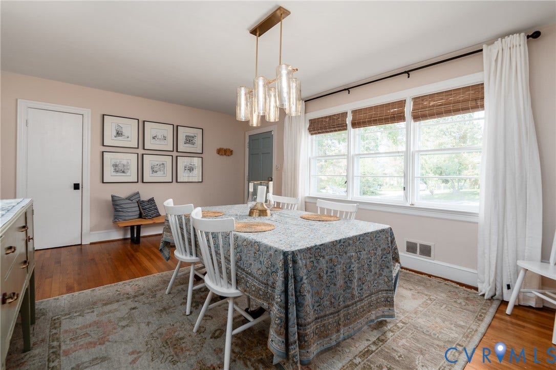Hardwood flooring, recessed windows with woven blinds, and a contemporary linear chandelier with glass accents