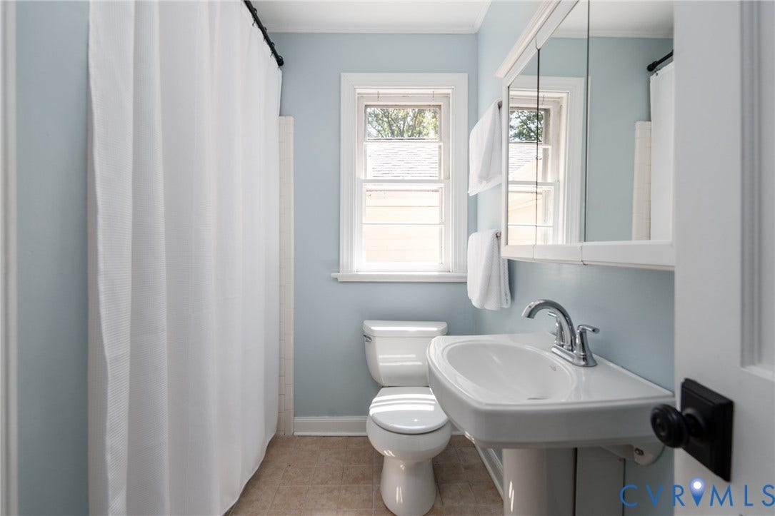 Pedestal sink with chrome faucet, double-pane window, and mirrored medicine cabinet