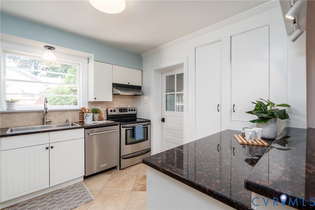 Kitchen featuring stainless steel appliances, dark stone countertops, tile backsplash, white cabinetry, and tile flooring