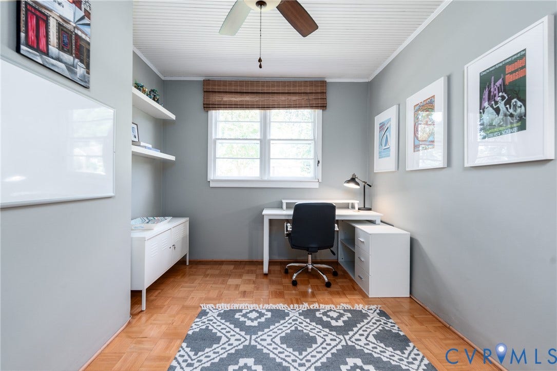 Wood-finish parquet flooring, white window trim, natural fiber window treatment, ceiling fan with light, and white built-in shelving