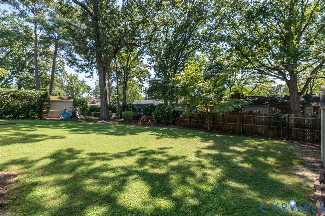 Expansive lawn with mature trees and a wood privacy fence