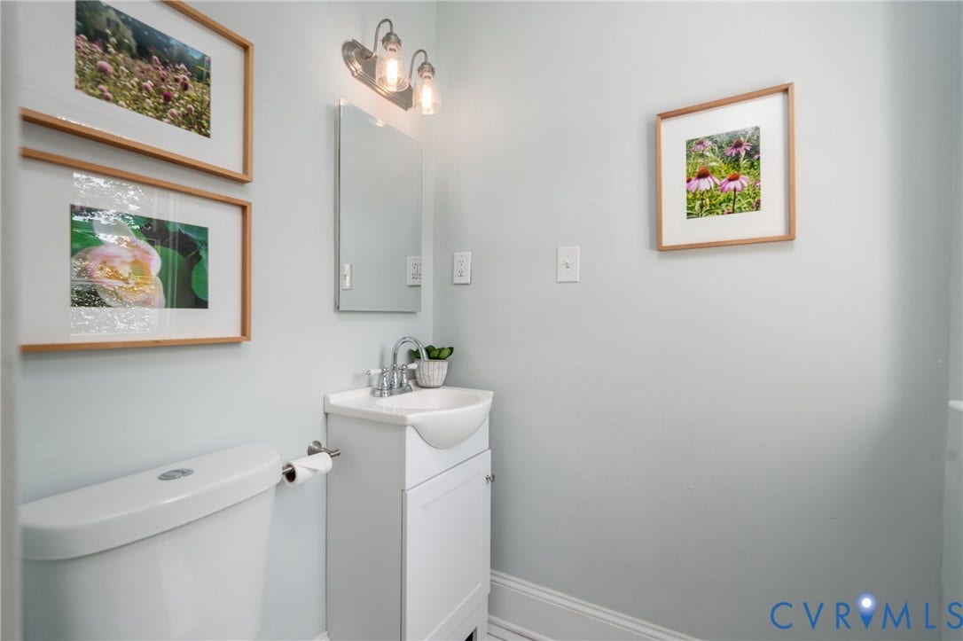 White vanity with an integrated sink and chrome faucet, rectangular mirror, and wall-mounted vanity light