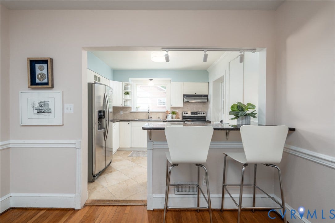 Kitchen with white cabinetry, stainless steel refrigerator, black countertops, and a tiled floor