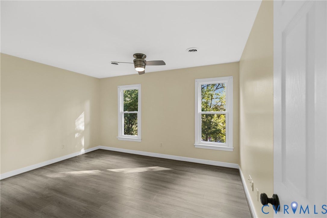 A ceiling fan and generous windows keep this bedroom bright and comfortable.