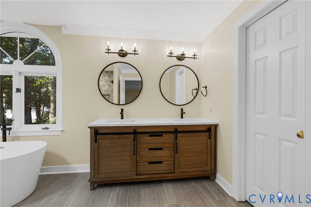 The ensuite primary bath features a soaking tub, dual vanities, and a separate frameless glass shower.