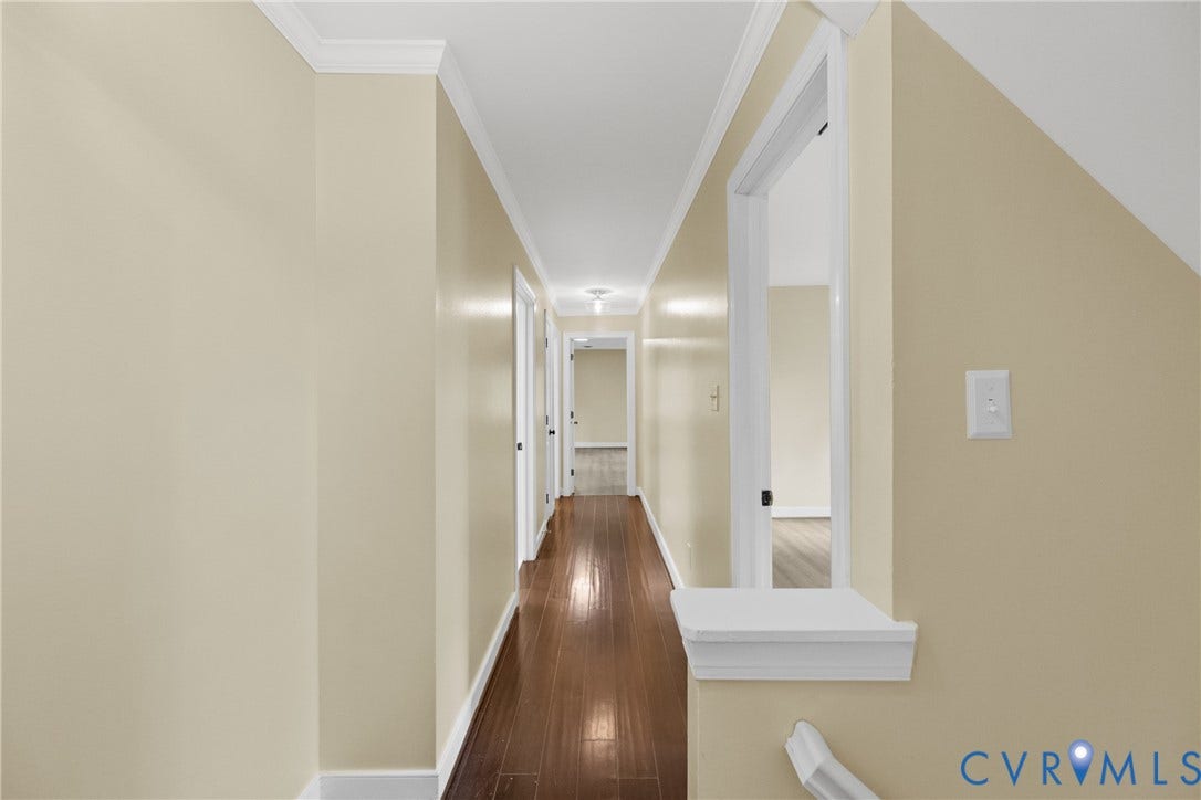 The upstairs hallway, finished with warm flooring, connects the primary suite to the additional bedrooms.