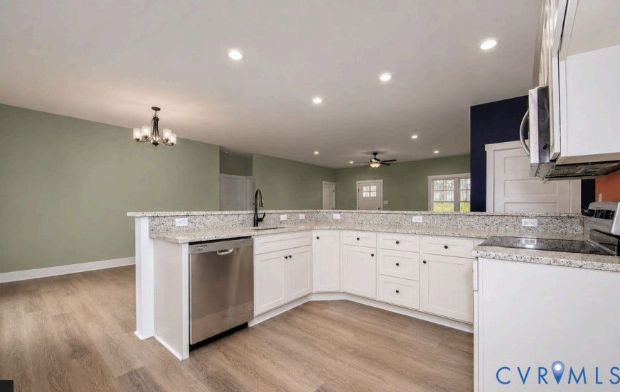 Kitchen featuring white cabinetry, light-toned countertops, a stainless steel dishwasher, and wood-finish flooring