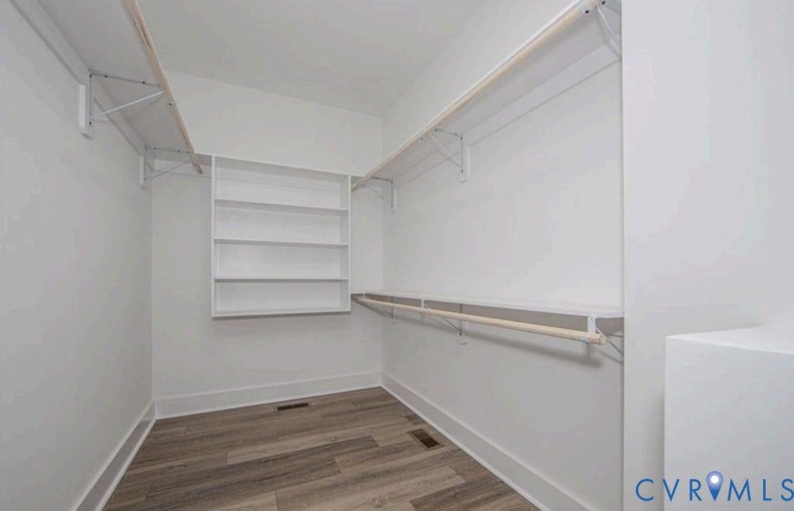 Walk-in closet with wood-finish flooring, built-in shelving, and multiple hanging rods