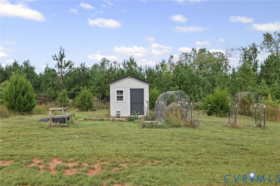 Detached storage shed with a dark gray door and white siding