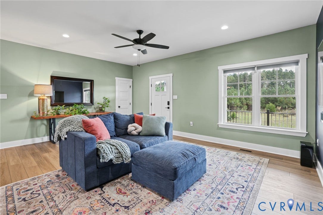 Recessed ceiling lights, wood-finish flooring, white window trim, white baseboards, and a ceiling fan with integrated lighting