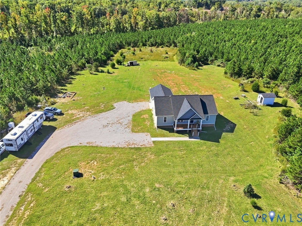 Expansive green lawn surrounding the property, bordered by dense mature trees