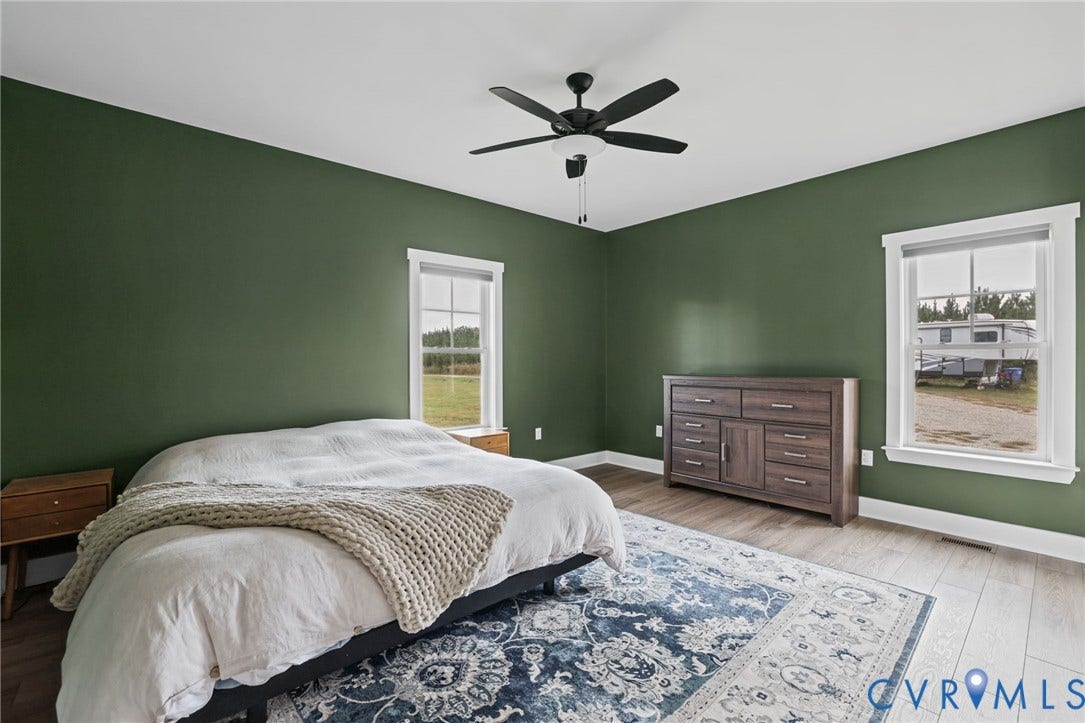 Spacious room featuring multiple windows, a ceiling fan with integrated lighting, and wood-finish flooring