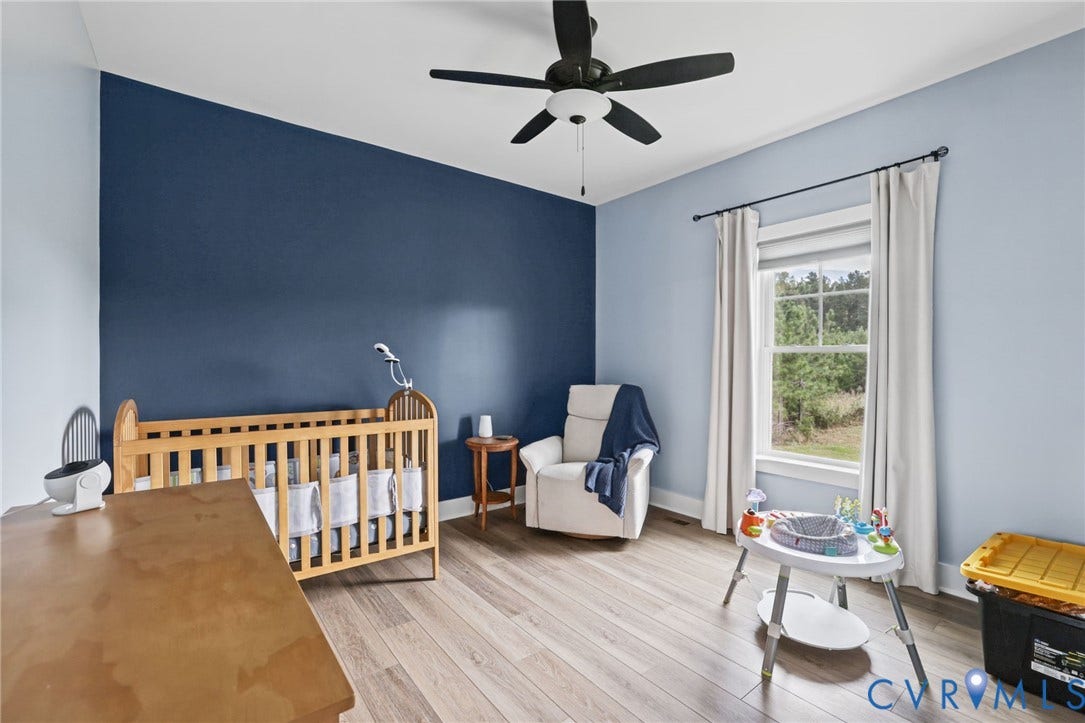 Bedroom 2, Wood-finish flooring, a ceiling fan with integrated lighting, a large window, light-toned walls, and an accent wall